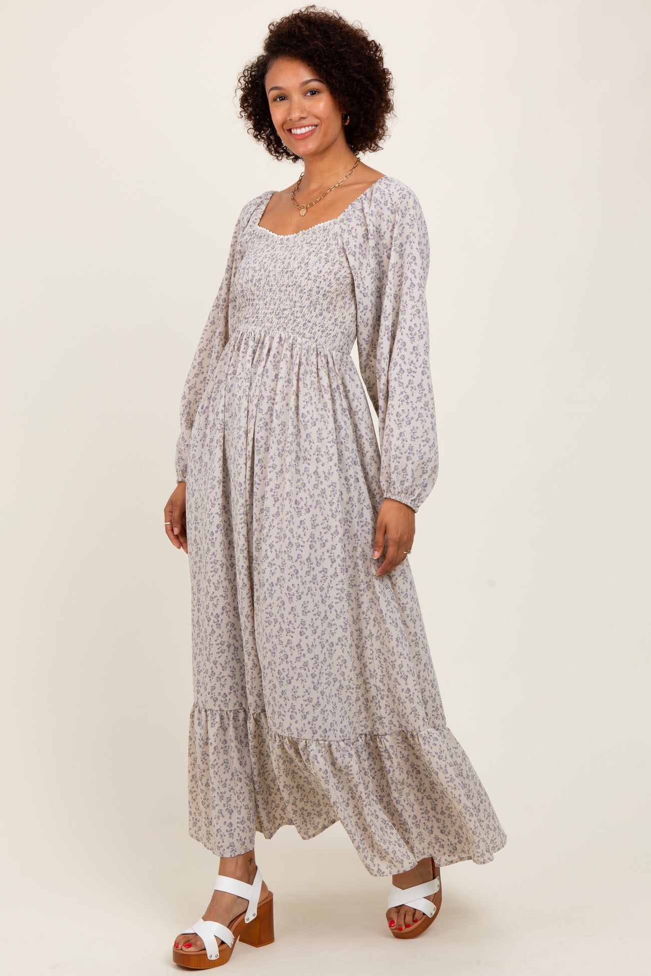 woman wearing a long floral maxi dress with long sleeves and a tiered skirt, posing and smiling