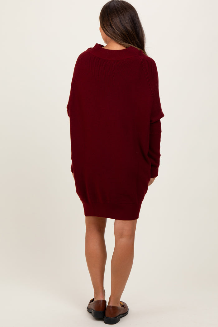 woman wearing a burgundy oversized maternity sweater dress from the back