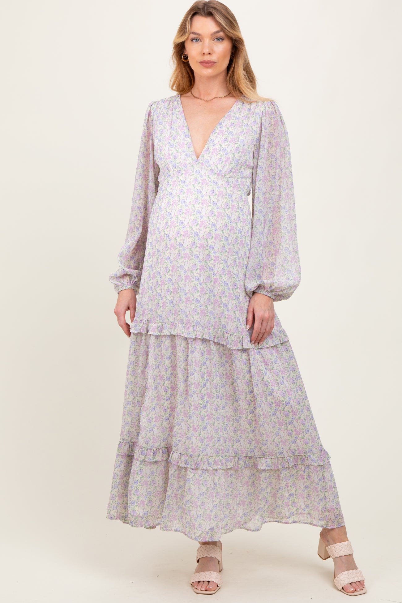 woman wearing a floral maternity maxi dress with a deep v-neck and balloon sleeves, highlighting her baby bump
