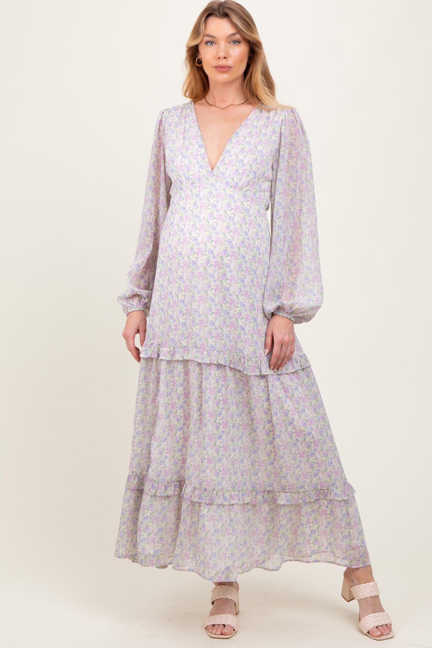 woman wearing a floral maternity maxi dress with a deep v-neck and balloon sleeves, highlighting her baby bump