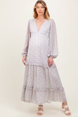 woman wearing a floral maternity maxi dress with a deep v-neck and balloon sleeves, highlighting her baby bump