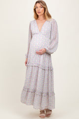 woman wearing a floral maternity maxi dress with puff sleeves and a deep v-neck, holding her baby bump