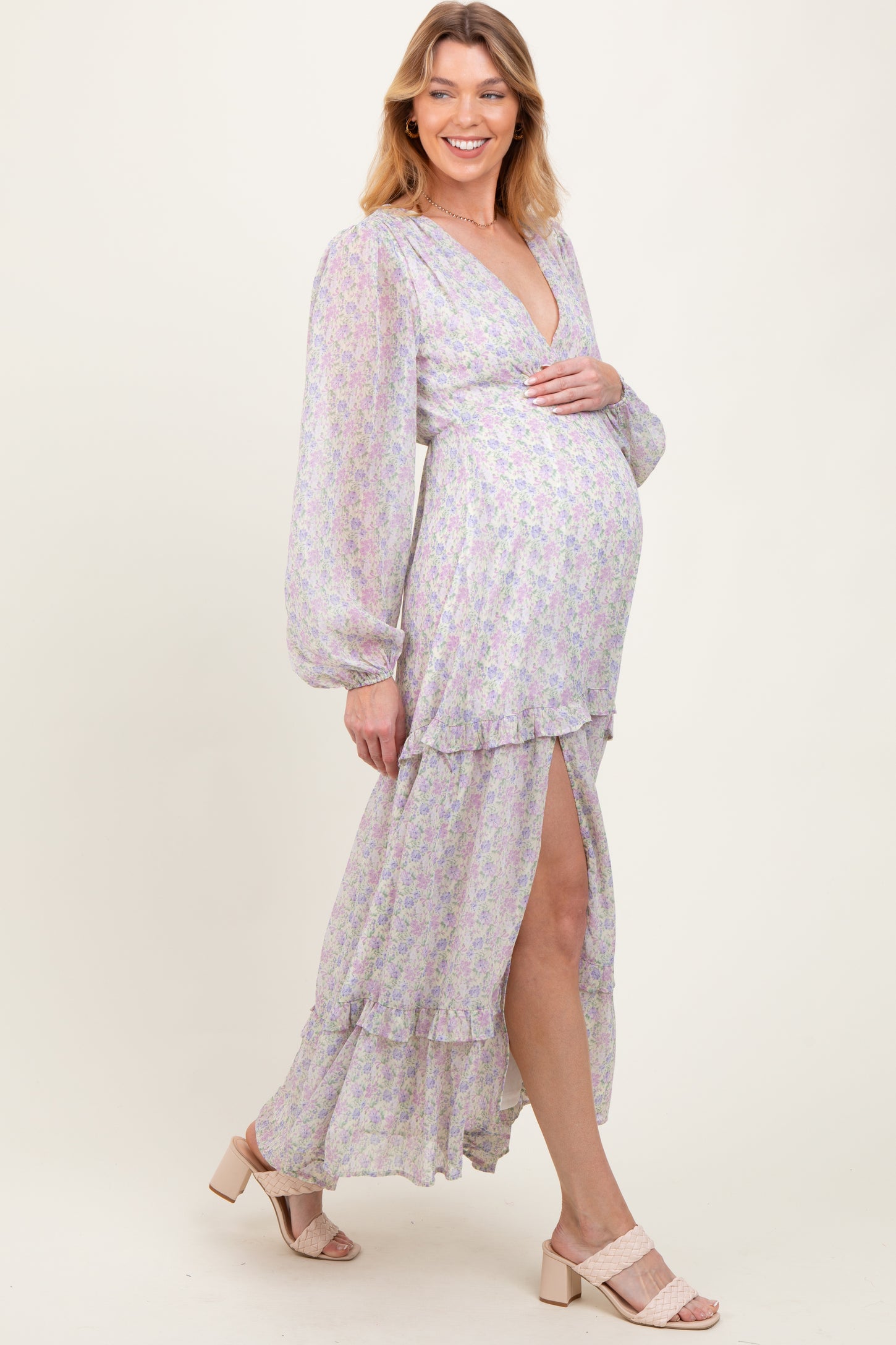 woman wearing a pastel floral maternity maxi dress with a deep v-neck and high slit, showing her baby bump