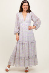 woman wearing a lilac floral maxi dress with puff sleeves and a tiered skirt, styled with a headband and white sandals