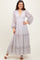 woman wearing a lilac floral maxi dress with puff sleeves and a tiered skirt, styled with a headband and white sandals