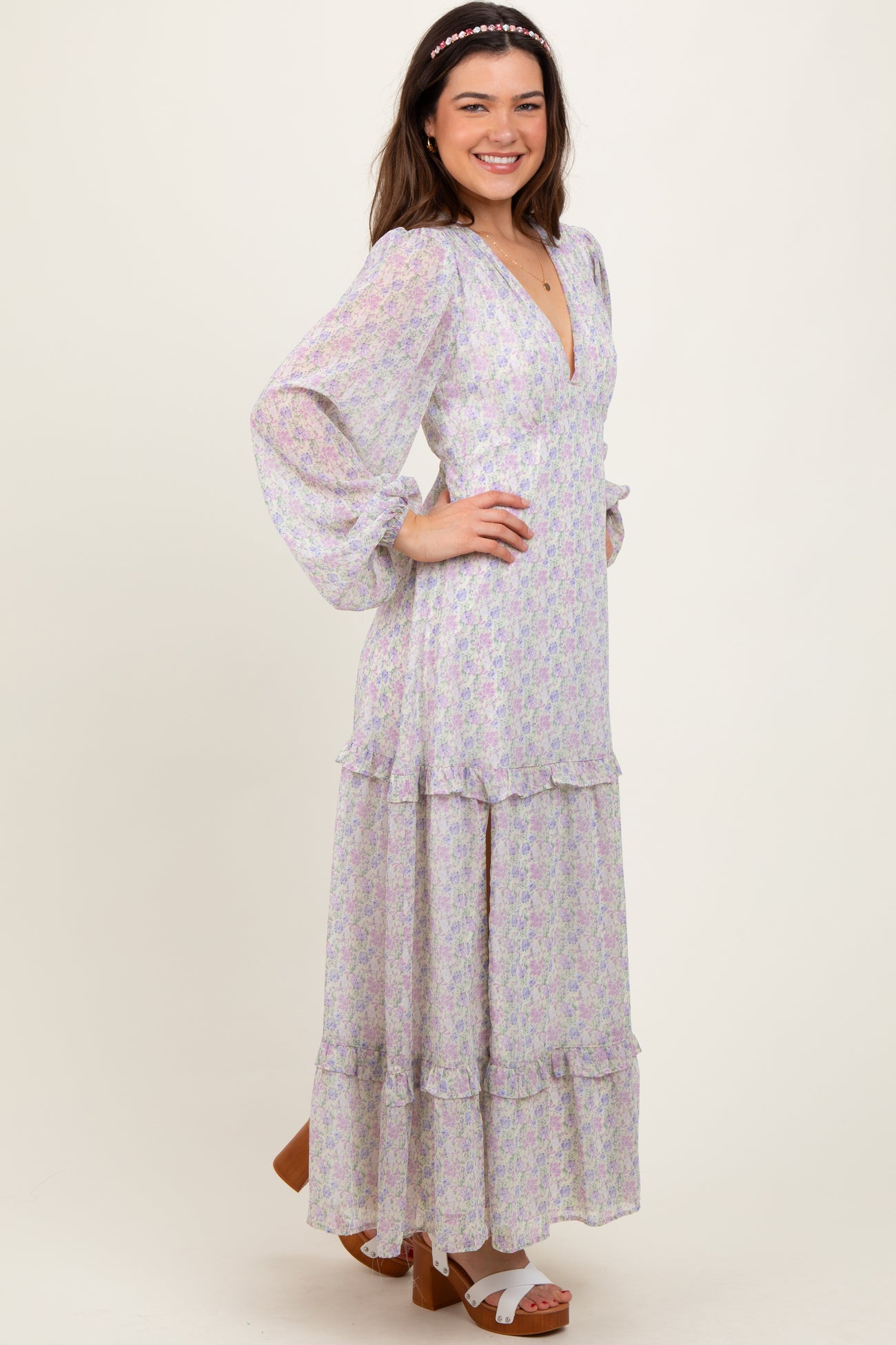 woman wearing a floral long sleeve maxi dress with ruffle details and a deep v-neckline, smiling and posing
