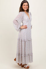 woman wearing a floral long sleeve maxi dress with ruffle details and a deep v-neckline, smiling and posing