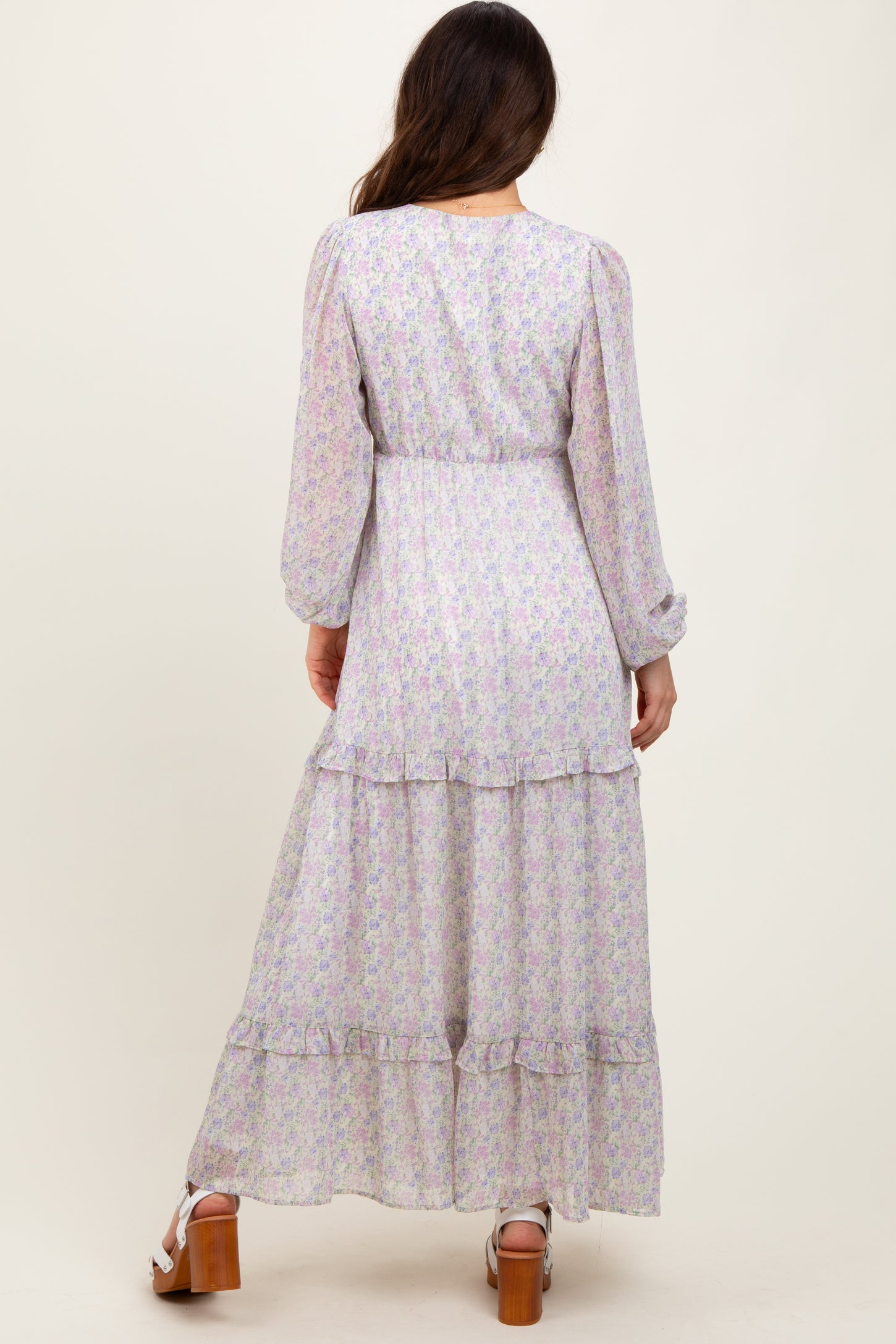 woman wearing a long-sleeve floral maxi dress with tiered ruffles, seen from the back