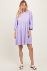woman wearing a lilac puff sleeve dress with a smocked waist and a flared skirt, standing on a neutral background