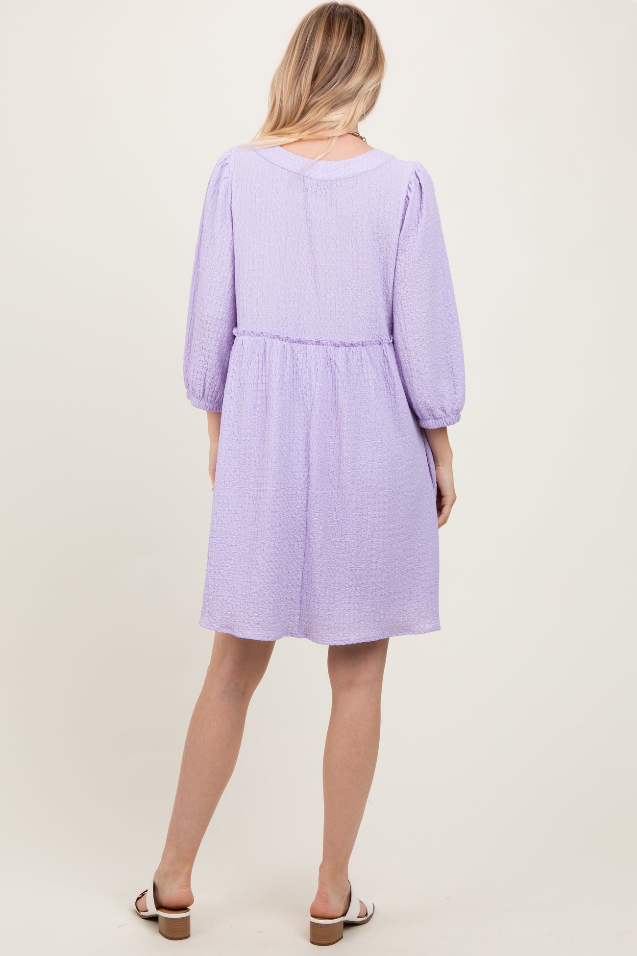 woman wearing a lavender puff sleeve dress with a cinched waist, shown from the back
