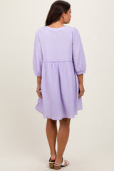 woman wearing a lavender maternity dress with three-quarter sleeves and a cinched waist, showing a relaxed fit