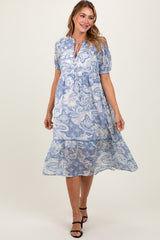 woman wearing a blue and white paisley print midi dress with puff sleeves and a tie neckline
