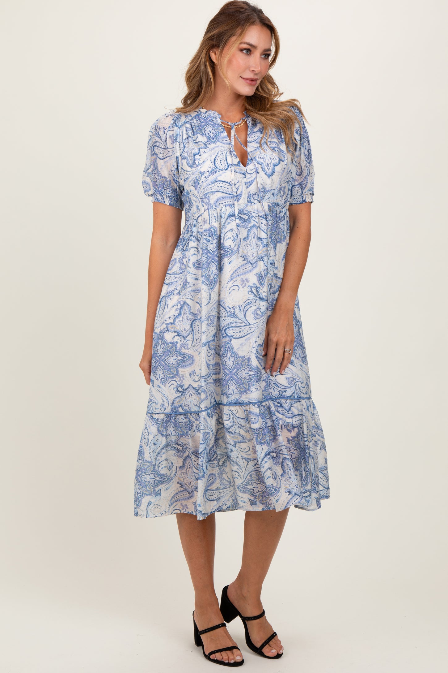 woman wearing a blue and white paisley print midi dress with short puff sleeves and a keyhole neckline