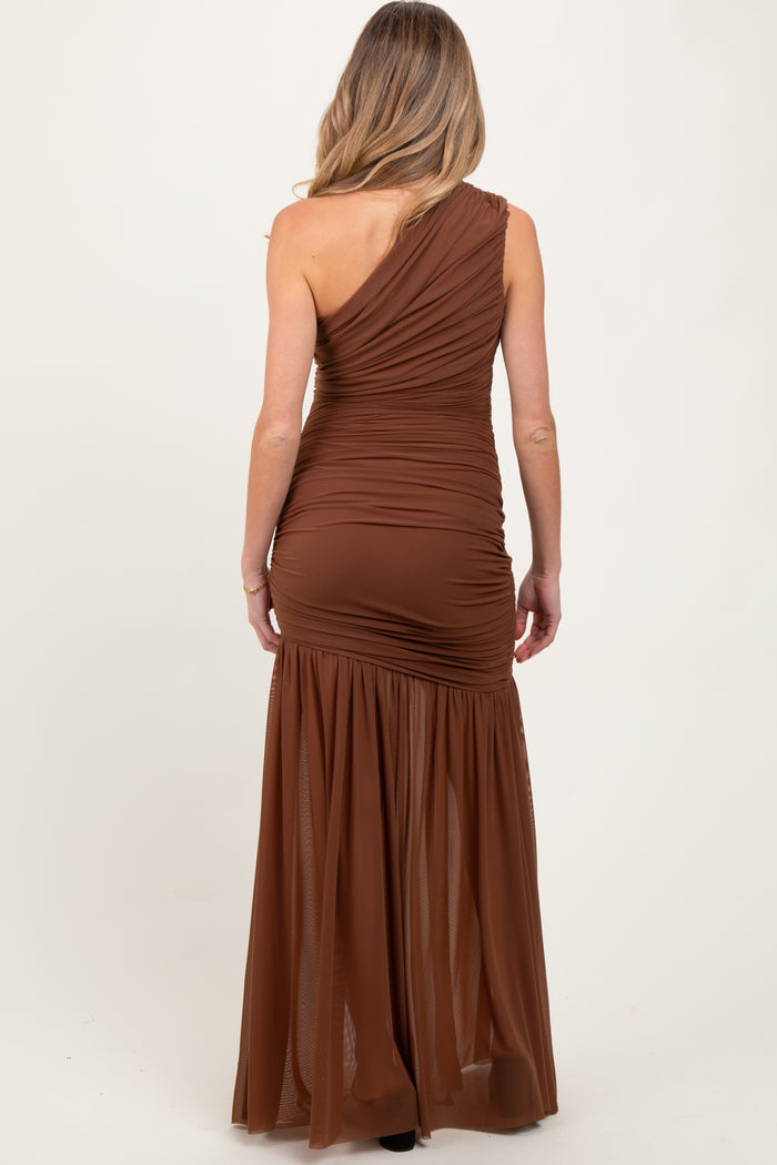 woman wearing a brown one-shoulder maternity dress with ruched detailing and a flowy skirt