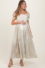 woman wearing a floral print white maternity dress with short puffy sleeves and holding her baby bump