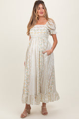 woman wearing a floral print white maternity dress with puff sleeves and pockets, showcasing her baby bump