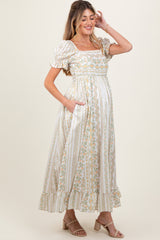 woman wearing a floral print maternity maxi dress with puff sleeves and pockets, showcasing her baby bump
