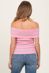 woman wearing a pink and blue striped off-the-shoulder maternity top with a fitted design and styled with high-waisted jeans