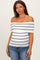 woman wearing a white and black striped off-shoulder maternity top and fitted blue jeans, showcasing her baby bump