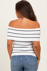 woman wearing a white off-the-shoulder maternity top with black stripes and blue jeans