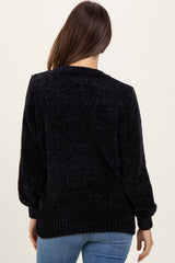 woman wearing a black maternity sweater with a textured knit and ribbed hem, viewed from the back