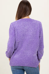 woman wearing a purple knit maternity sweater with a relaxed fit, visible back detailing, paired with blue jeans