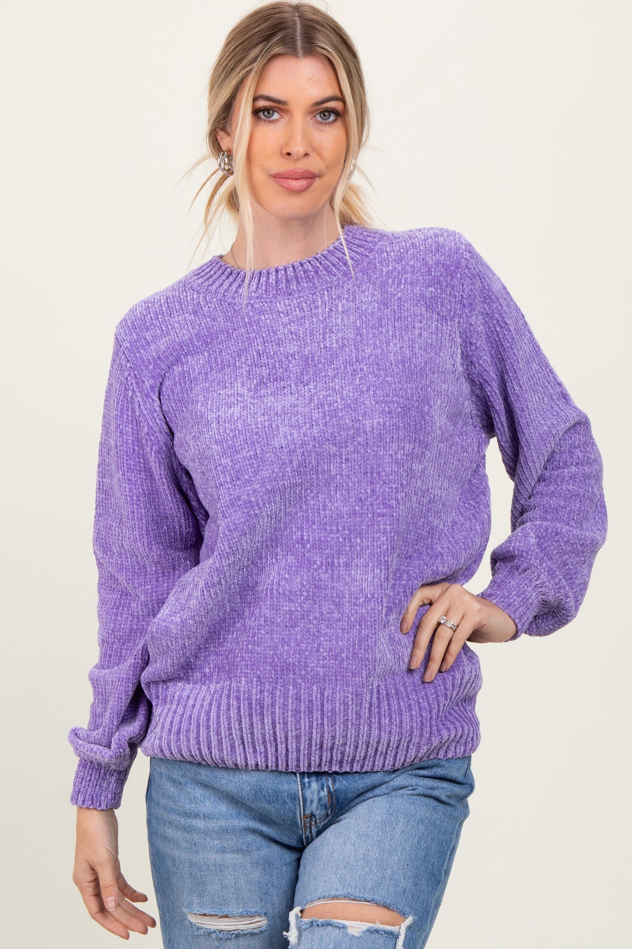 woman wearing a purple oversized knit sweater with a ribbed hem and cuffs paired with distressed jeans