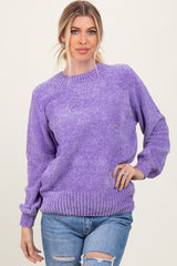woman wearing a purple oversized knit sweater with a ribbed hem and cuffs paired with distressed jeans