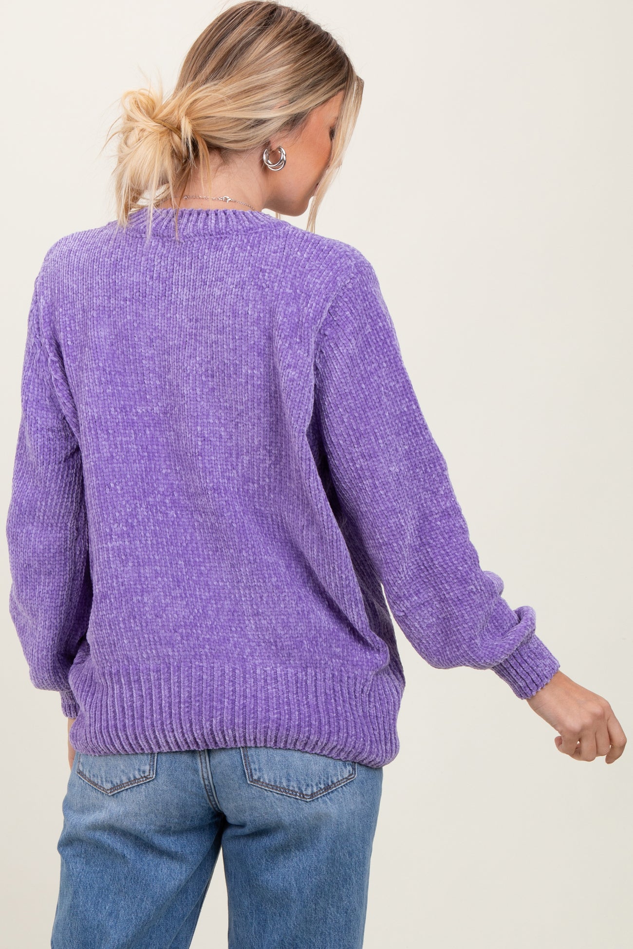 woman wearing a purple oversized sweater with ribbed details and casual jeans, viewed from the back