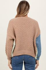 woman wearing a pastel color block knit sweater with a textured pattern and long sleeves, facing away from the camera
