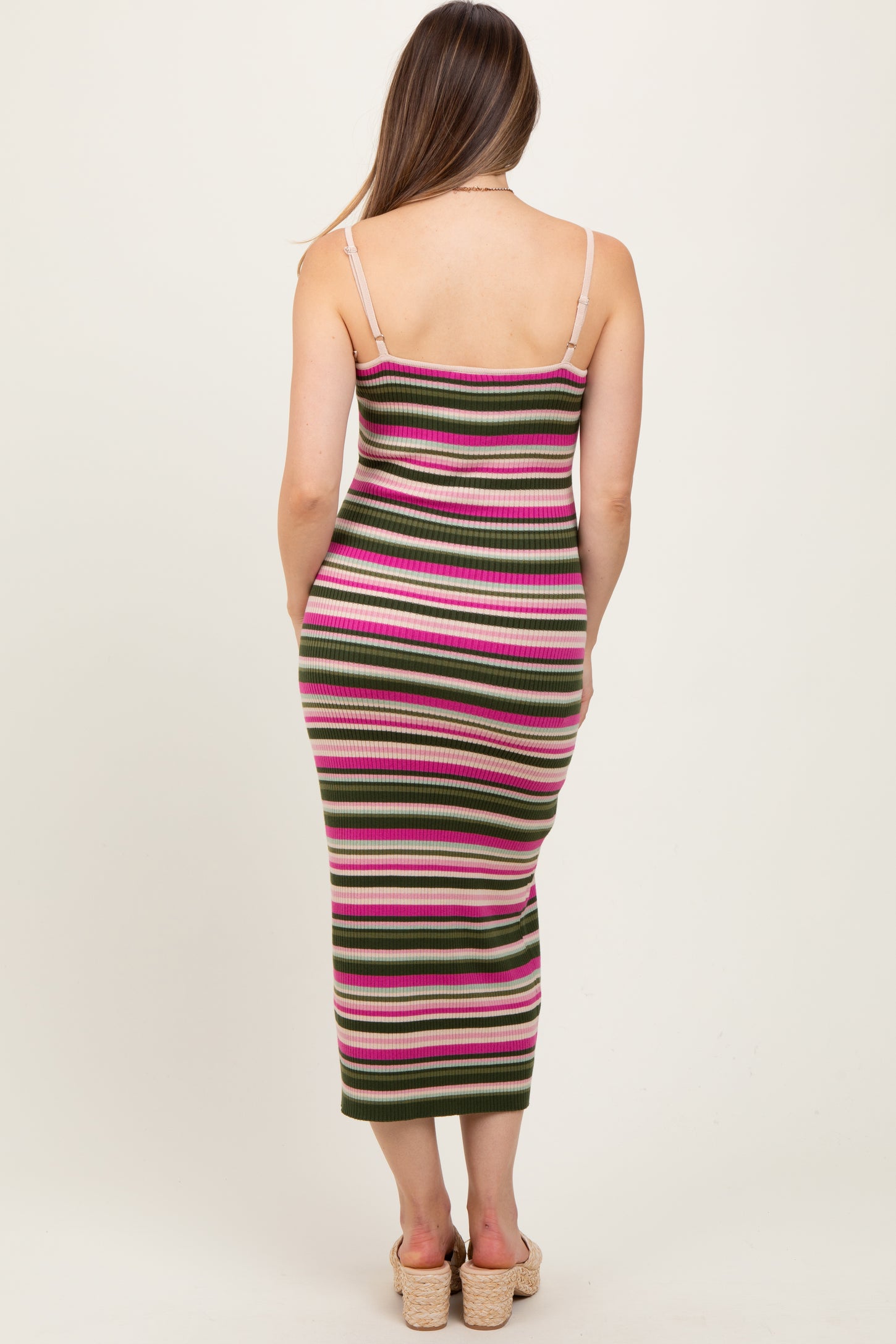 woman wearing a fitted green, pink, and white striped maternity dress with spaghetti straps and a below-the-knee length