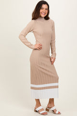 woman wearing a beige long sleeve ribbed midi dress with white striped hem and side slits, standing with one hand on her hip