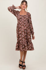 woman wearing a floral pink maternity dress with long sleeves and a tiered ruffle hem, showcasing a baby bump