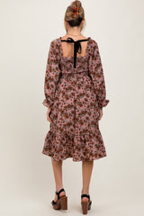 woman wearing a floral maternity dress with a smocked back and tie detail, featuring long sleeves and a ruffled hem