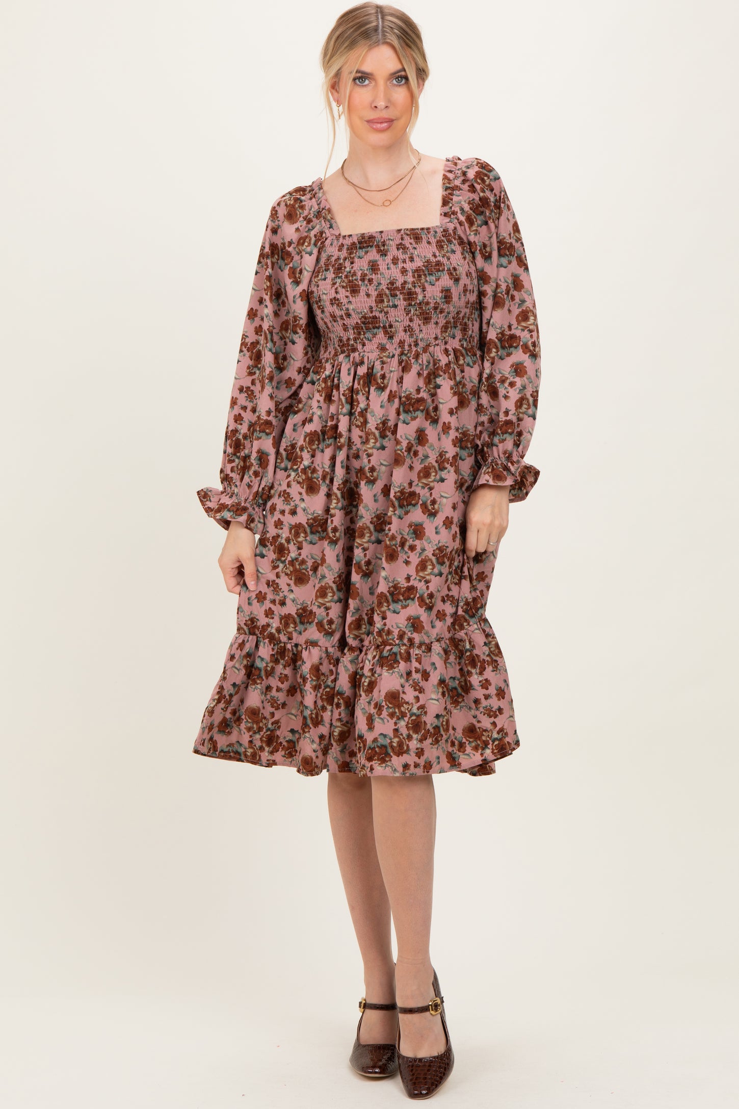woman wearing a pink floral smocked midi dress with long sleeves and ruffled hemline