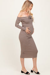 woman wearing a brown and cream striped off-shoulder maternity dress with a flower detail and holding her baby bump