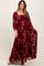 woman wearing a burgundy maternity maxi dress with floral prints and long sleeves, showcasing a baby bump