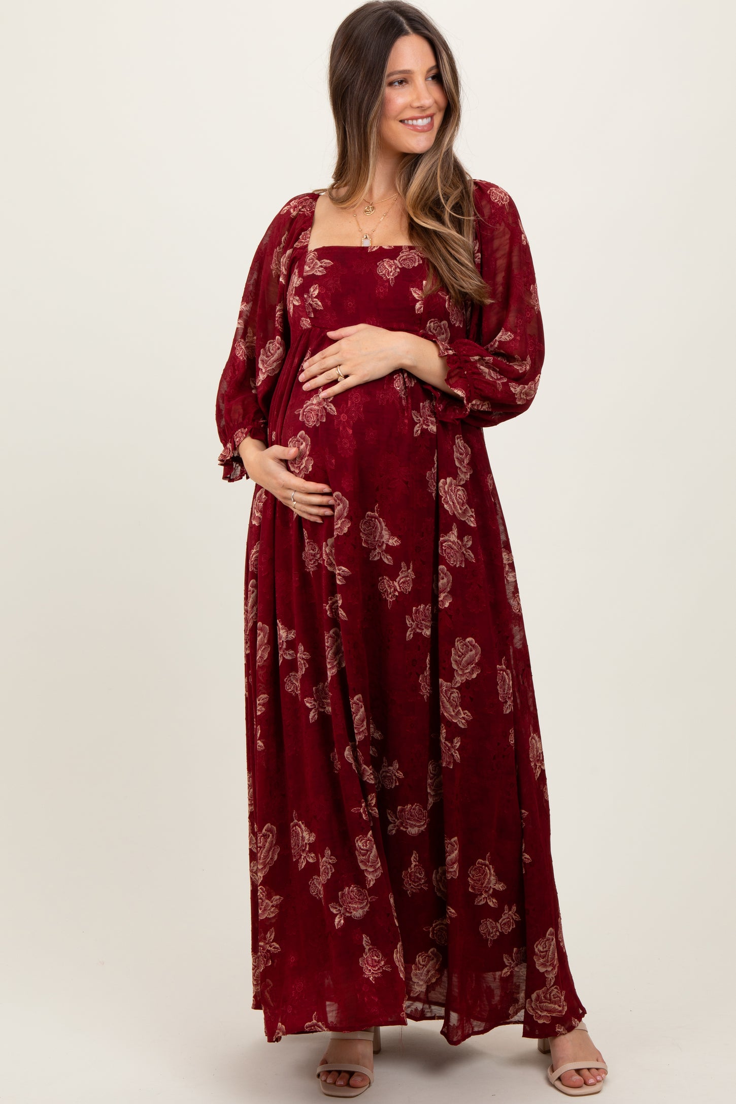woman wearing a burgundy floral maternity maxi dress and holding her baby bump
