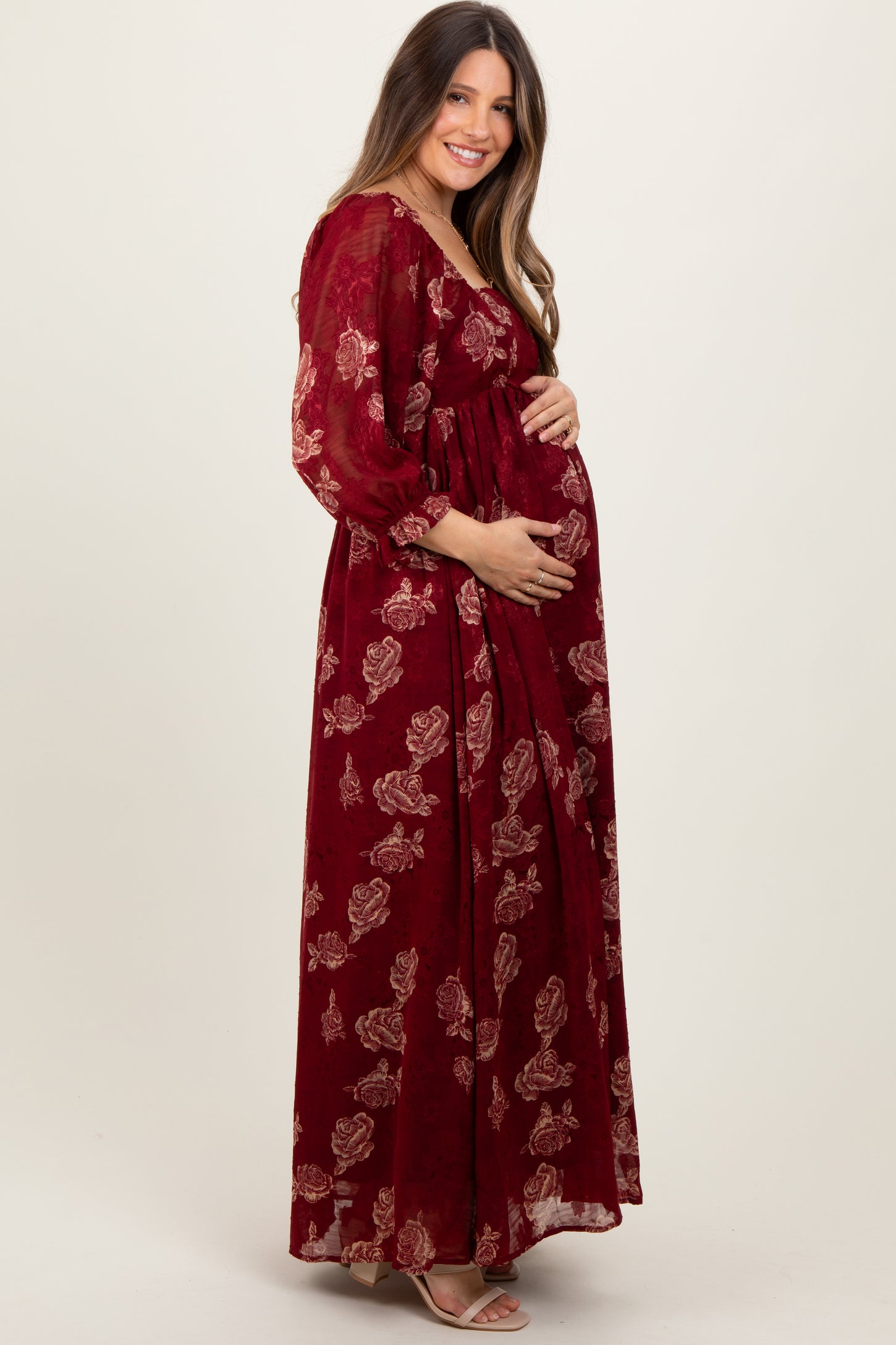 woman wearing a burgundy floral maternity maxi dress and holding her baby bump