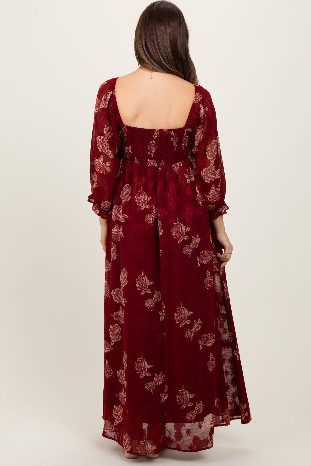 woman wearing a burgundy floral maternity maxi dress with long puff sleeves and a smocked back