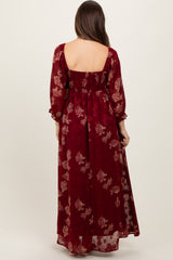 woman wearing a burgundy floral maternity maxi dress with long puff sleeves and a smocked back
