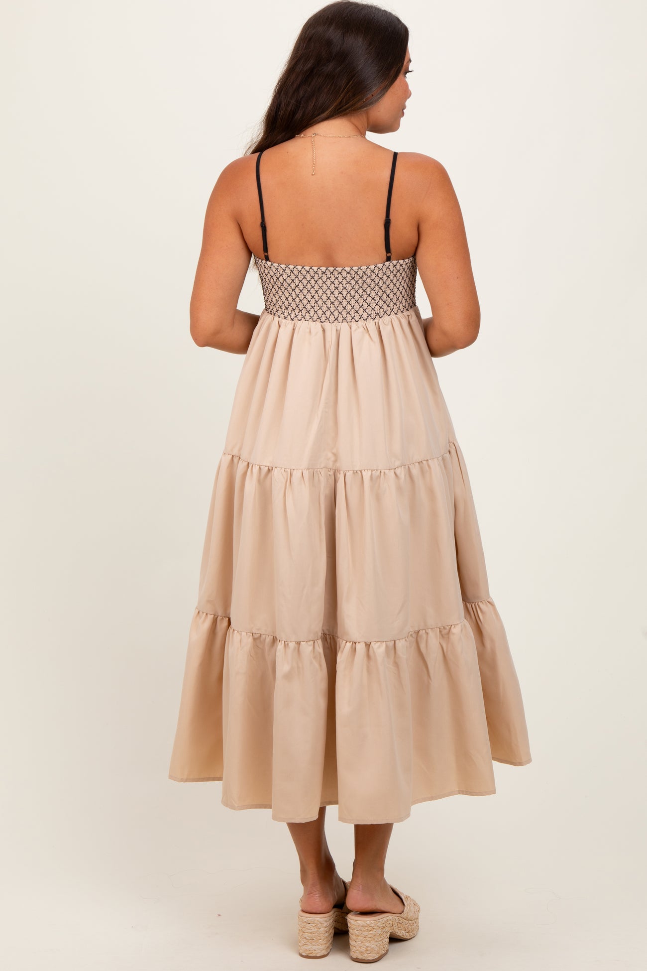 woman wearing a beige tiered maternity maxi dress with adjustable spaghetti straps and a smocked back