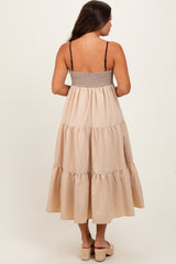 woman wearing a beige tiered maternity maxi dress with adjustable spaghetti straps and a smocked back