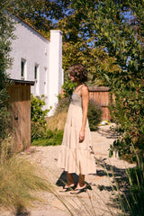 woman wearing a beige tiered maxi dress with a patterned bodice, standing in a garden setting