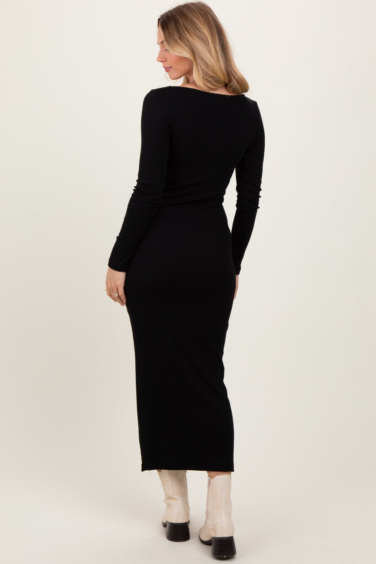 woman wearing a black ribbed long sleeve maxi dress, view from the back showcasing a fitted silhouette