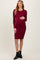 woman wearing a burgundy long sleeve maternity dress and holding her baby bump