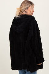 woman wearing a black fuzzy hooded cardigan with a ribbed texture, showcasing the back view and relaxed fit