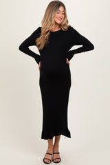 woman wearing a black ribbed long sleeve maternity dress with a ruffled hem and showing her baby bump