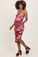 woman wearing a fitted red and pink floral maternity dress, showcasing her baby bump and styled with chunky heels