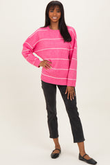 woman wearing a pink striped oversized sweater and black cropped pants, standing with a smile